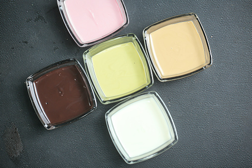 A photograph of four distinct colors of paint jars placed neatly on top of a wooden table.