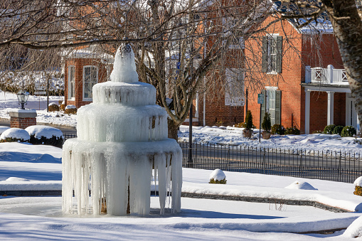 Abingdon, Virginia, USA - January 21, 2024: A water fountain iced over surrounded with snow in the front yard of the Martha Washington Hotel downtown Abingdon.