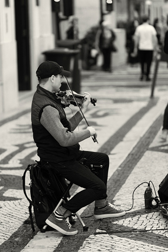 Lisbon, Portugal - December 9, 2023: A street musician plays a violin at the Rua Augusta street in Lisbon downtown.