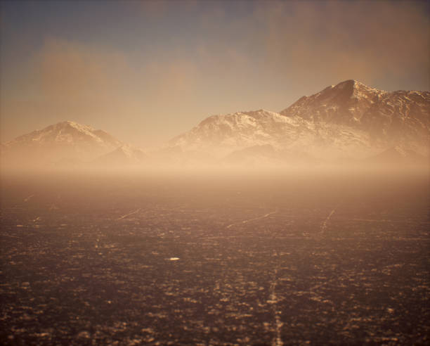 Frozen lake with snow mountains in mist under sky with some clouds.