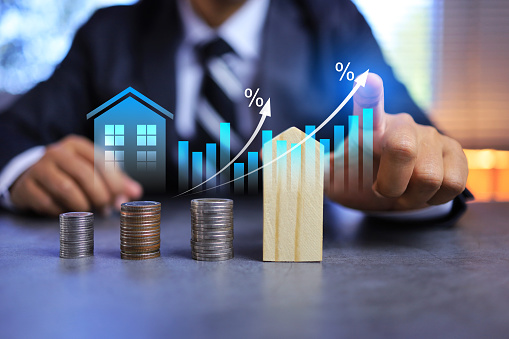 Real estate investment concept with businessman pointing on growth graph and coin stacking to get profit from property