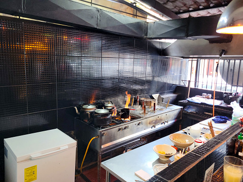 A snapshot of a bustling Japanese restaurant kitchen with flames leaping from the stove