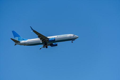 Boeing 737-800 flies against blue spring sky to Adler airport. Close-up. POBEDA AIRLINES. Aircraft landing gear and flaps extended. Sochi, Russia - May 18, 2021