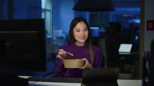 DS Woman working in the call center at night and having dinner while on a videocall