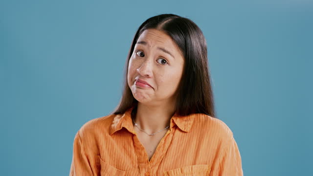 Face, shrug and confused woman, puzzled and doubt in studio isolated on a blue background mockup space. Portrait, uncertainty and Asian person with question, clueless and unsure facial expression
