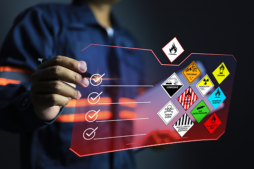 Security officer tick check mark on virtual screen to inspect the storage of dangerous goods in the warehouse for operator safety such as flammable gas, explosions, radioactive, toxic gases