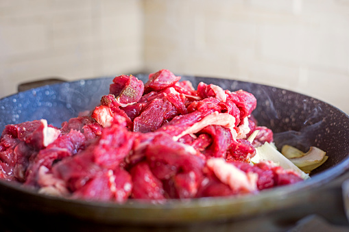raw fresh meat cut into pieces in a frying pan. Cook at home