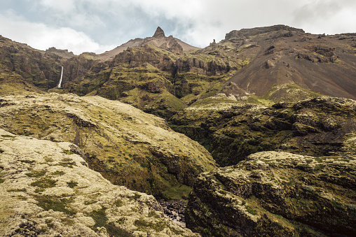 Iceland landscape with grass and moss covered rocks and waterfall