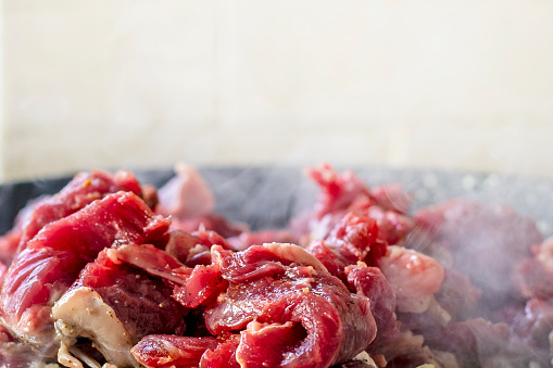 cook raw fresh meat cut into pieces in a frying pan. Cooking at home in the kitchen