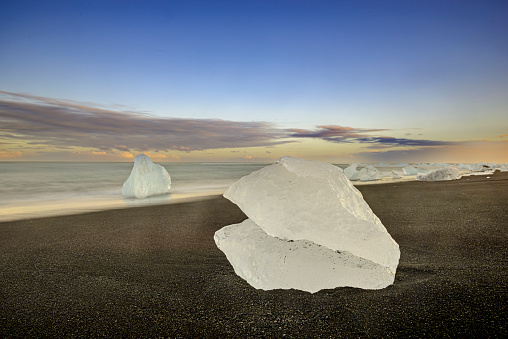 Delicate piece of Ice washed up on the ash  beach also known known as Jokulsarlon diamond Beach near the glacier lagoon of Jokulsarlon, Iceland during sunset over the Atlantic Ocean.