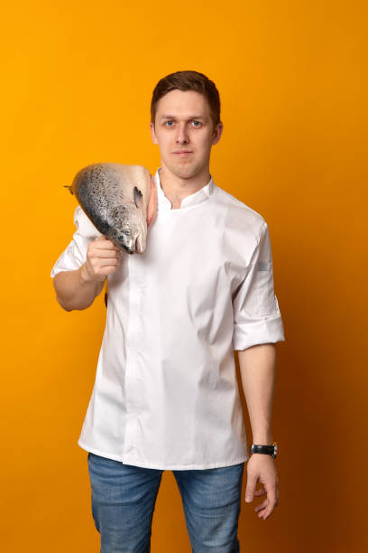 Male chef holding raw fish.