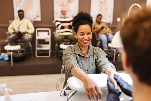 Happy female client doing a manicure at a beauty salon