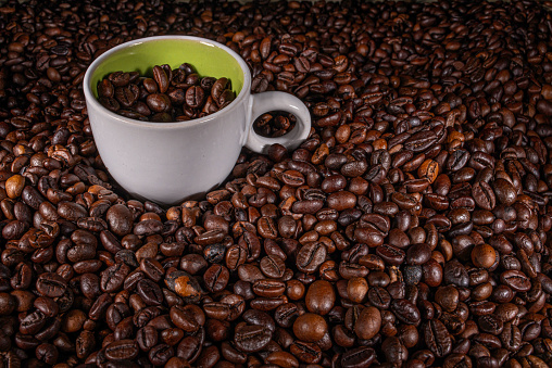 Background with roasted coffee beans and a ceramic cup