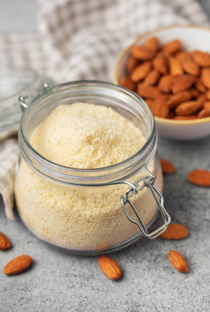 Fresh almond flour in a  glass jar and almonds