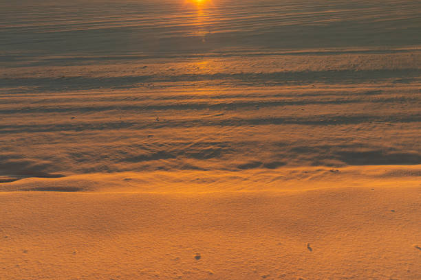 winter field covered with snow at sunset, beautiful multicolored sky at sunset in winter