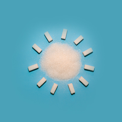 Sugar cubes in the form of a sun on a blue background. Creative food flat lay.