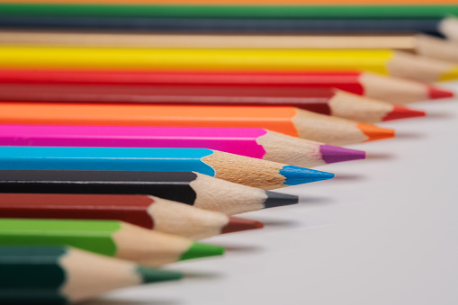 colored pencils lie in a horizontal  row like a rainbow. traces of these pencils are drawn on a white background. Creative idea. Back to school, purchasing school supplies. Education concept.