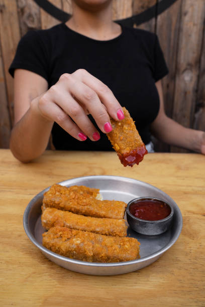 istock A woman dipping a fried mozzarella stick in a spicy sauce 2027690340