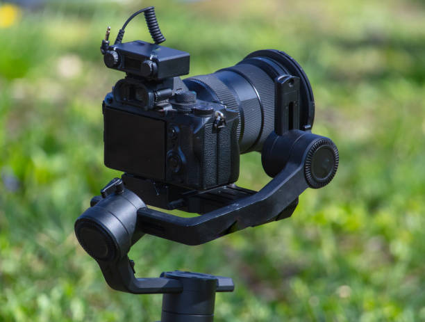 istock Professional video camera on tripod in green grass. Shallow depth of field 2027698251