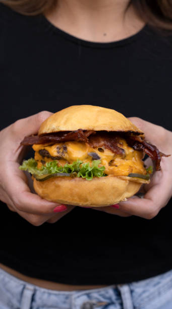 istock A woman holding a cheddar cheese and bacon burger 2027699339