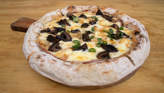 Mushrooms pizza. Top view of a pizza with provolone and mozzarella cheese, tomato sauce and champignons on the wooden table.