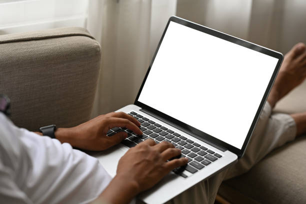 istock Close up of Asian man using laptop for work while sitting on sofa, Empty screen of laptop. 2027711453