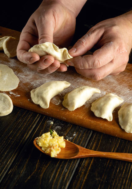 istock The chef makes a dumpling from dough and potatoes with his hands. Concept of preparing delicious dumplings on the kitchen table for lunch 2027711970