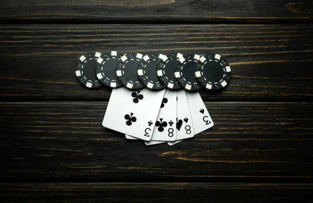 Photo of A gambling and popular poker game with a combination of two pairs. Chips and cards on a dark vintage table in a poker club