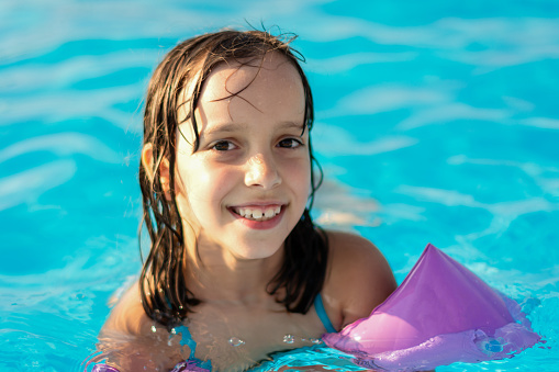 A cute happy little girl in the swimming pool.