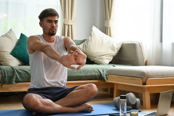 istock Handsome Young Asian man doing arm stretching exercise at home. 2027732924