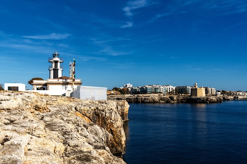 Ciutadella, Spain - 26 January, 2024: view of the Ciutadella llighthouse and Sant Nicolau Castle at the harbour entrance in Ciutadella
