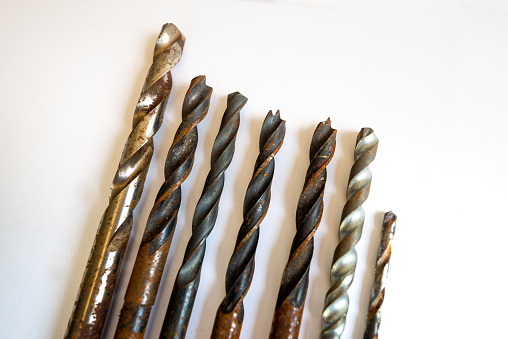 Close up of assorted rusty drill bits of various sizes, length and thickness isolated on white background. Home DIY tool equipment used for drilling brick, plaster, concrete, masonry.