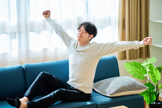 ソファーベッドで目を覚ます青年 - リフレッシュ ストックフォトと画像