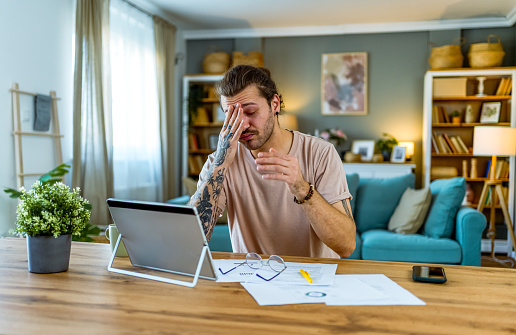 Young worried man manage finances at home