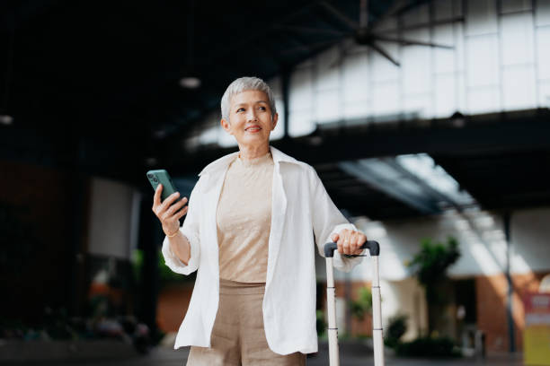 Senior Asian female business traveller using smartphone