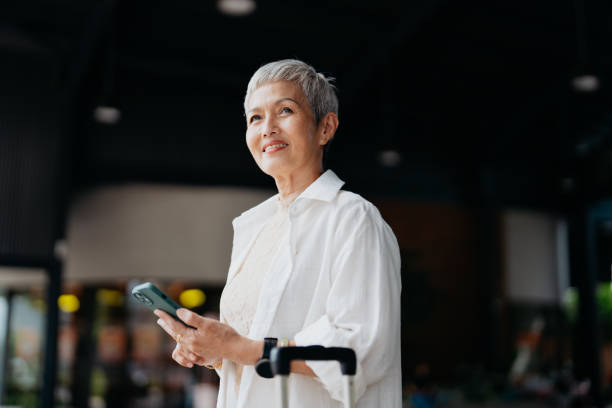 istock Senior Asian female business traveller using smartphone 2027802784