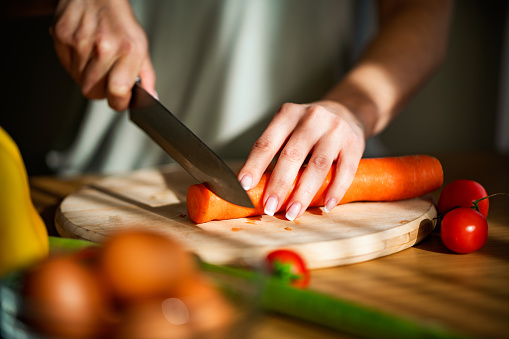 Close-up of a unrecognizable woman chopping vegetables in the kitchen