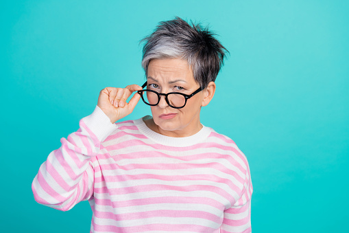 Photo of unsure suspicious lady wear striped sweater hand arm spectacles looking you isolated turquoise color background.