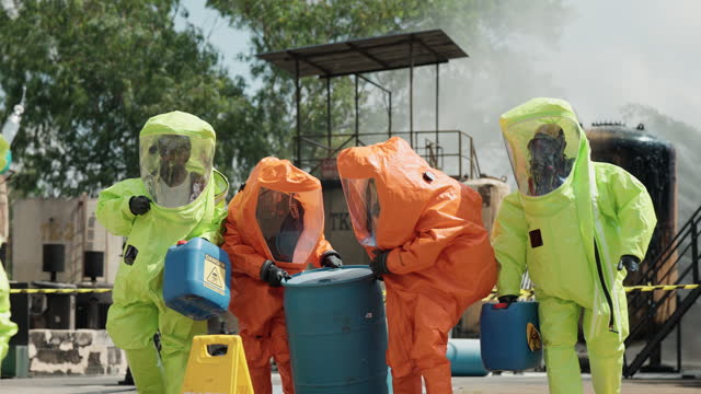 Safely Extracting Chemical Drum from Oil Plant. A skilled group of expert worker in hazmat suit including advanced protective gear, in action as they work collaboratively to remove a chemical drum from the oil plant, enveloped in a curtain of water.
