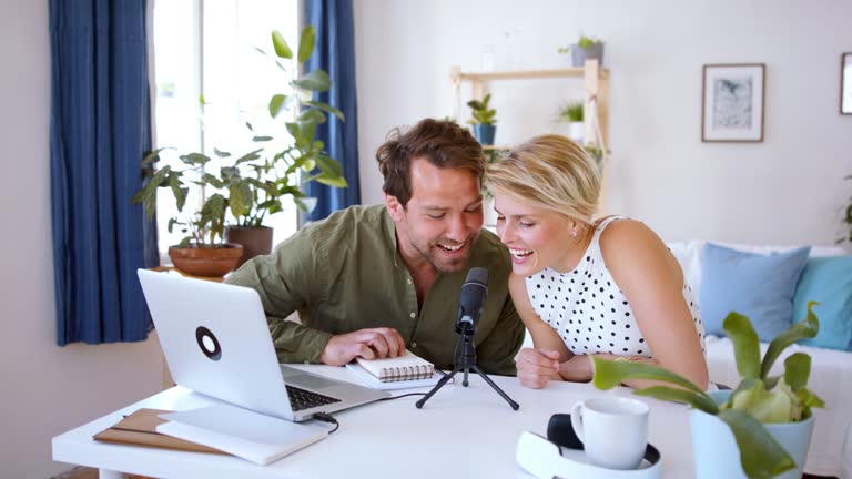 Happy couple with microphone having video call on laptop indoors at home.