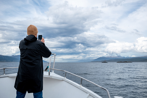 Tourist taking a photo of the incredible Beagle Channel in Argentine Patagonia. Beautiful landscape of southern Argentina. Tourist taking a photo of the Beagle Channel from a boat