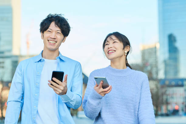 istock Smiling man and woman with smartphone in hand 2027880740
