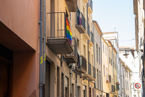 Flag with rainbow colors on the balcony of old house with much beautiful flowers in Spain city.