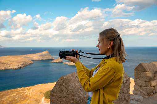 A woman photographer takes pictures of Lindos Bay.