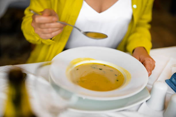 A woman eats puree soup in a restaurant.