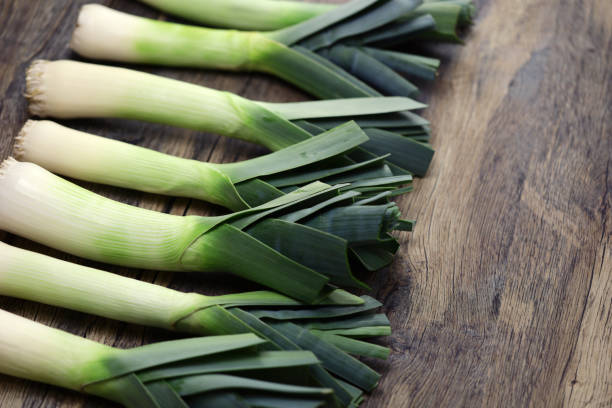 istock freshly harvested leeks isolated on wooden background. copy space 2027944162