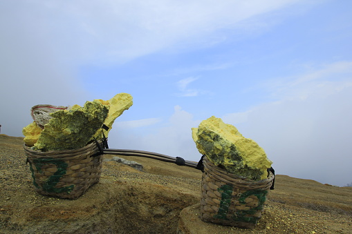 Sulfur stone is placed in a basket to be transported by miners in Ijen Crater, East Java, Indonesia