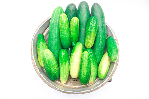 Collection of large fresh green cucumbers in a bowl isolated on white background. Long cucumber from Asian agriculture