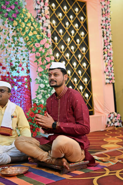 istock Groom with folded hands sitting on the floor with the priest during rituals 2027991257