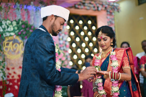 In a tender moment of the wedding celebration, the groom lovingly slides the ring onto the bride's finger, sealing their bond with the promise of eternity. With eyes full of devotion and hands intertwined, they embark on a journey of lifelong partnership, marked by this timeless exchange of vows and affection.